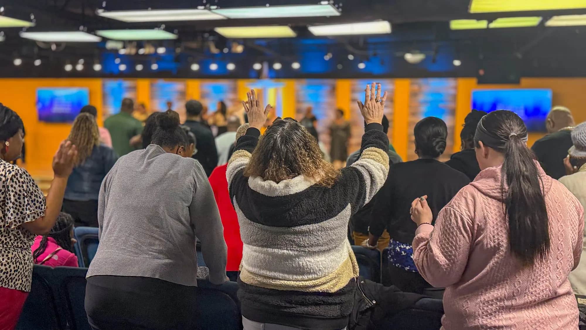 The congregation at Canton Christian Fellowship in worship, hands raised toward the stage